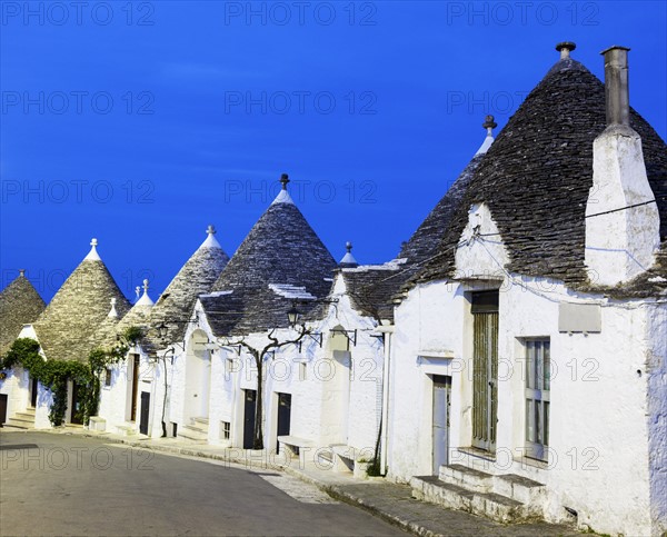 Trulli houses along street under blue sky