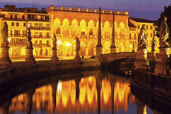 Illuminated buildings of Prato della Valle with statues at dusk