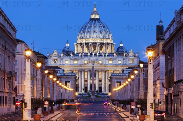 Illuminated St. Peter's Basilica with asphalt road in foreground at dusk
