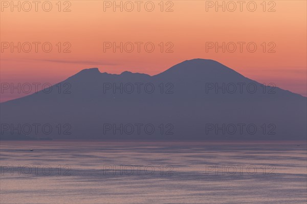 Silhouette of mountains with sea in foreground at sunset