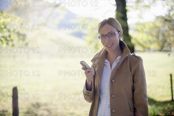 Smiling woman in beige coat with mobile phone