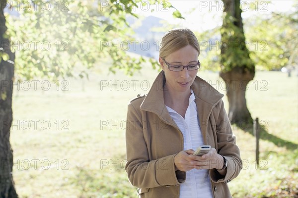 Woman in beige coat using mobile phone