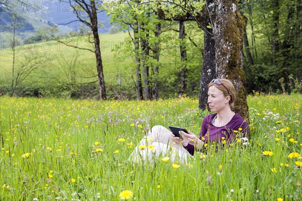 Woman using e-reader in meadow