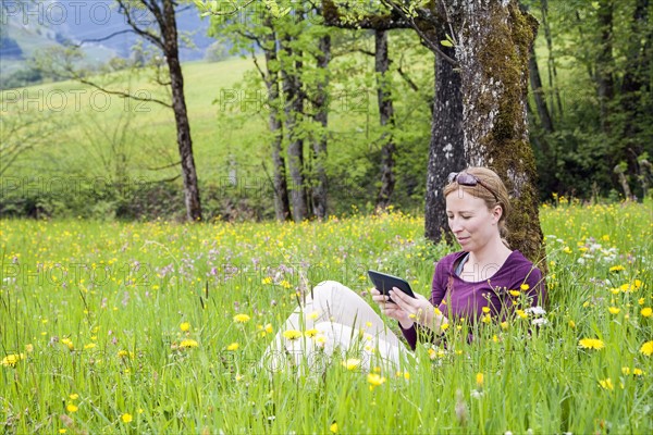 Woman using e-reader in meadow