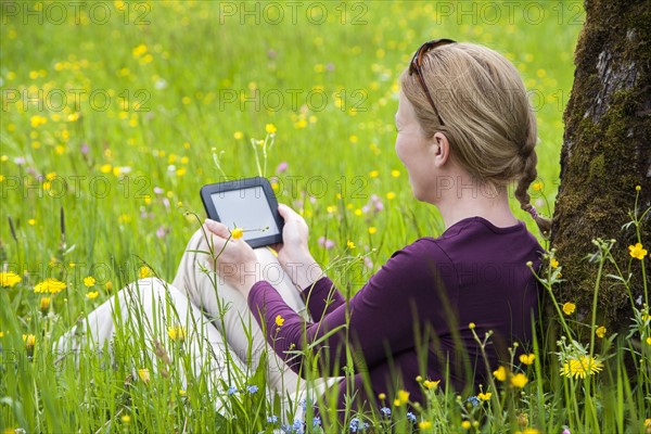 Woman using e-reader in meadow