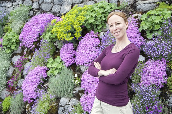 Smiling woman standing against flowerbed