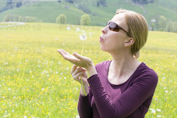 Woman blowing on dandelion