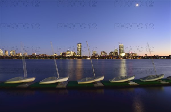 Sail boats in row on pier, cityscape in background