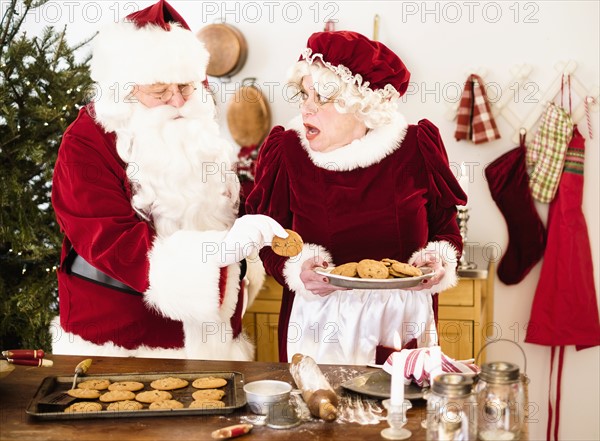 Santa stealing gingerbread cookie from Mrs. Claus.