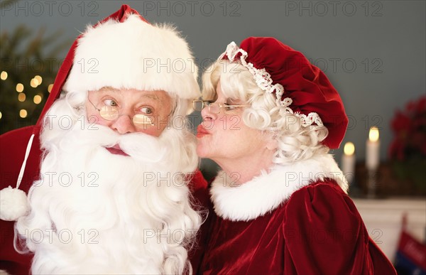 Mrs. Claus kissing Santa on cheek.