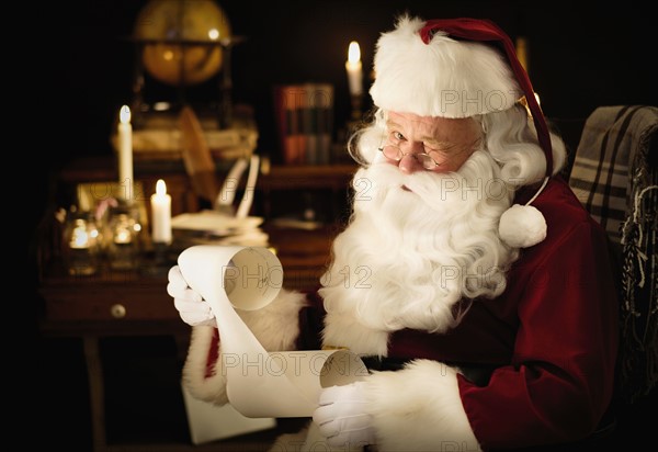 Portrait of Santa Claus reading child's letter and winking.