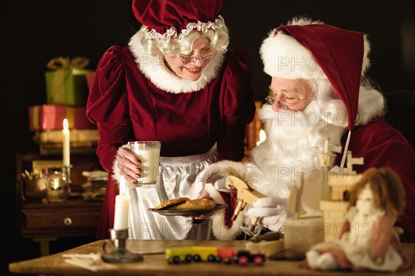 Mrs. Claus bringing homemade cookies to Santa Claus.