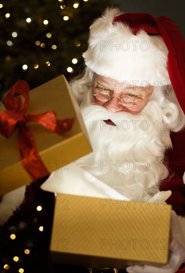 Portrait of Santa Claus opening Christmas presents.