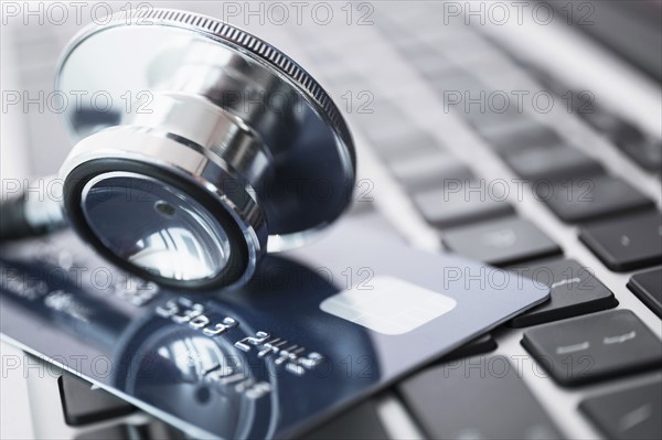 Stethoscope and credit card lying on laptop.