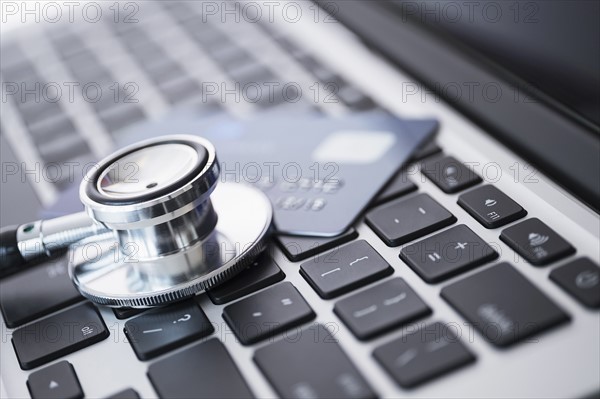 Stethoscope and credit card lying on laptop.