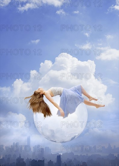 Young woman floating on bubble over cityscape. USA, New York, New York City.