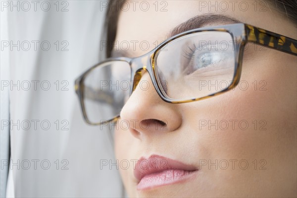 Close up of young woman with blue eyes wearing glasses.