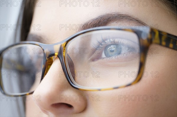 Close up of young woman with blue eyes wearing glasses.