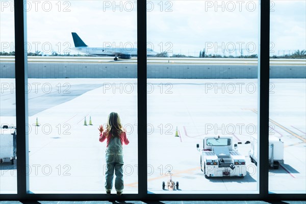 Girl (2-3) looking through window at airport.