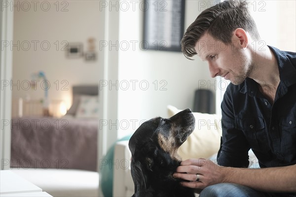 Man playing with dog in living room.