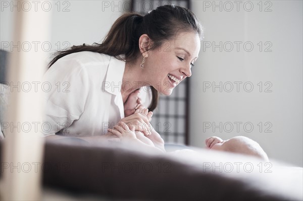 Mother playing with baby daughter (2-5 months).