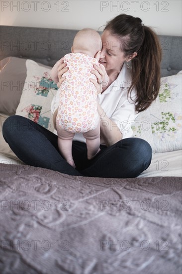 Mother playing with baby daughter (2-5 months) in bedroom.