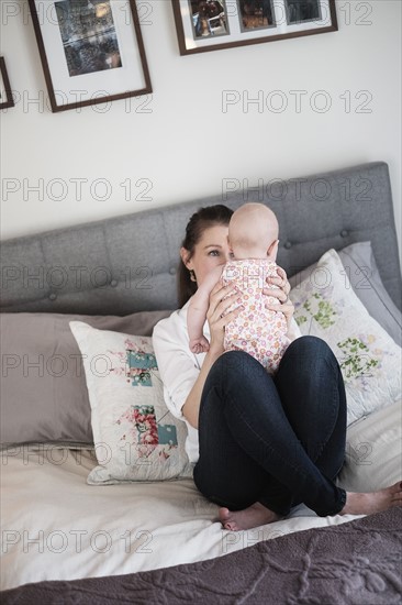 Mother playing with baby daughter (2-5 months) in bedroom.