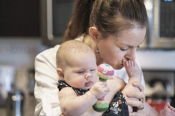 Mother kissing baby daughter's (2-5 months) feet.