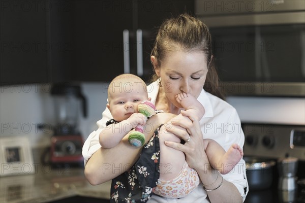 Mother kissing baby daughter's (2-5 months) feet.