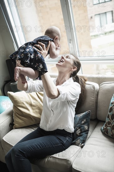 Mother playing with baby daughter (2-5 months) in living room.