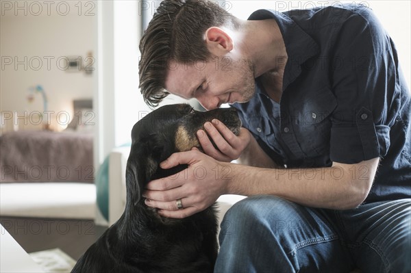 Man playing with dog in living room.