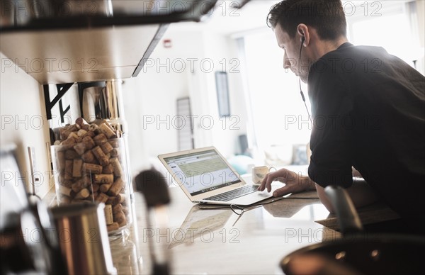 Man working on laptop computer in kitchen.