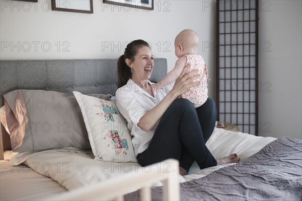 Mother playing with baby daughter (2-5 months) in bedroom.