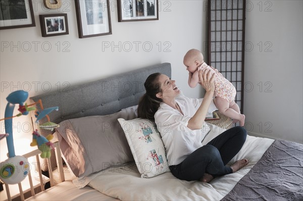 Mother playing with baby daughter (2-5 months) in bedroom.