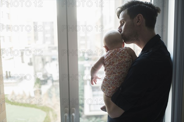 Father looking through window with daughter (2-5 months).