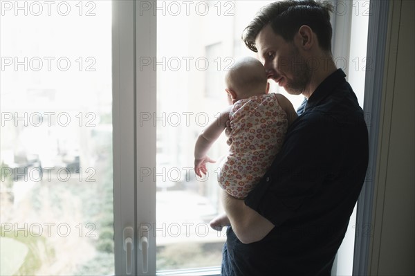 Father looking through window with daughter (2-5 months).