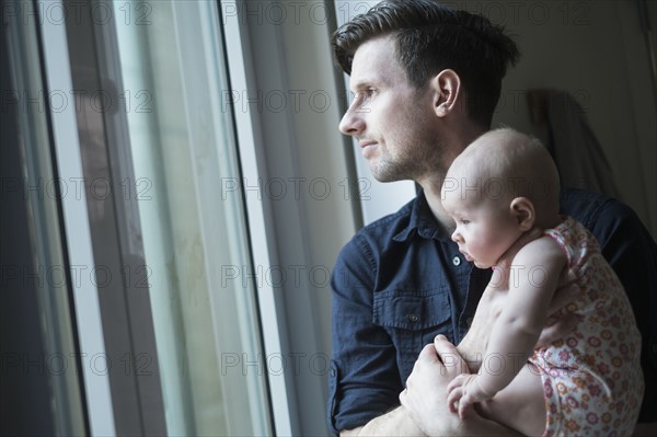 Father looking through window with daughter (2-5 months).