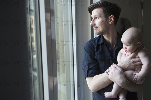 Father looking through window with daughter (2-5 months).