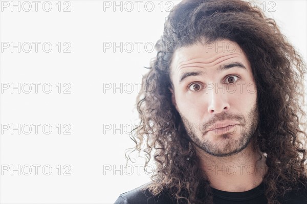 Portrait of young man with long curly hair.