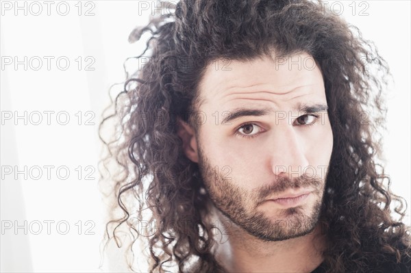 Portrait of young man with long curly hair.