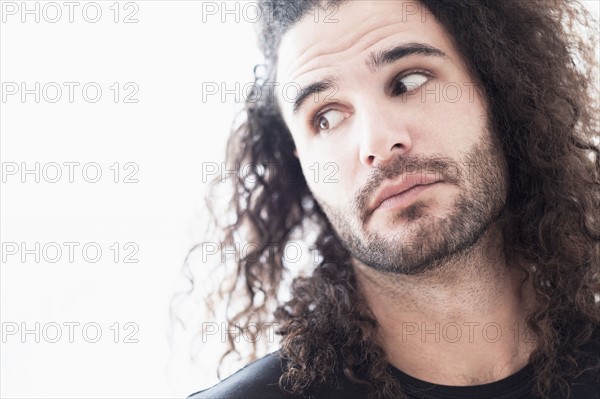 Portrait of young man with long curly hair.