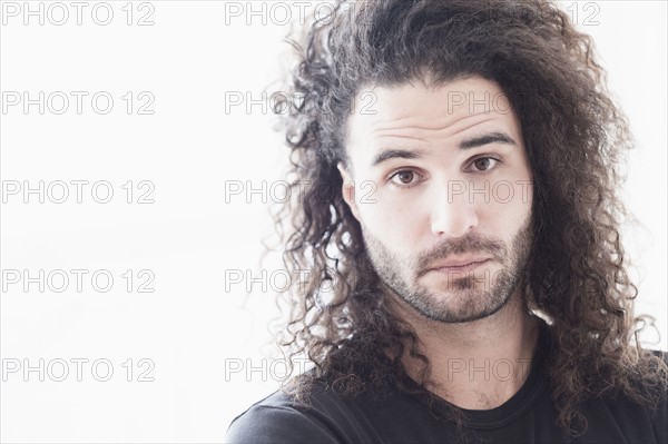 Portrait of young man with long curly hair.