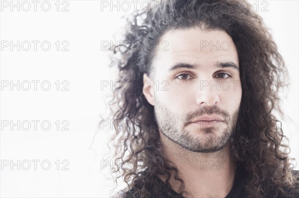 Portrait of young man with long curly hair.