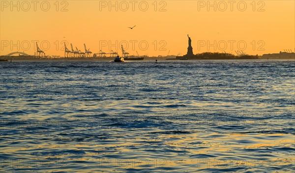 Silhouette of Statue of Liberty at sunset. USA, New York, New York City.