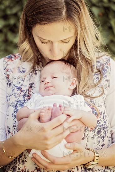 Mother holding and kissing daughter (2-5 months)