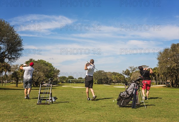 Three men playing golf