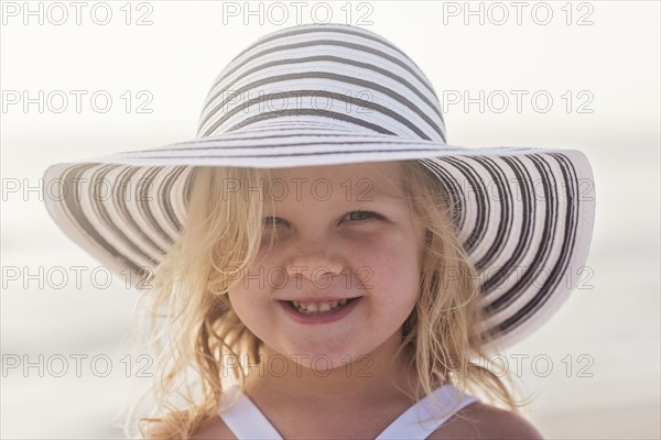 Portrait of girl (4-5) in sunhat at beach