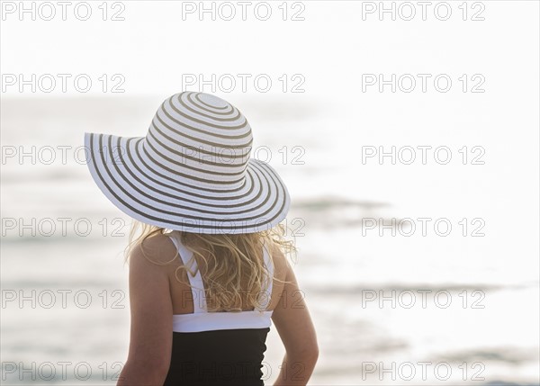 Girl (4-5) in striped sunhat by sea