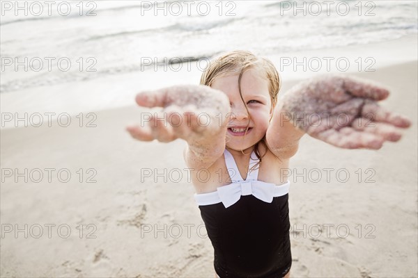 Girl (4-5) standing on beach showing her dirty hands