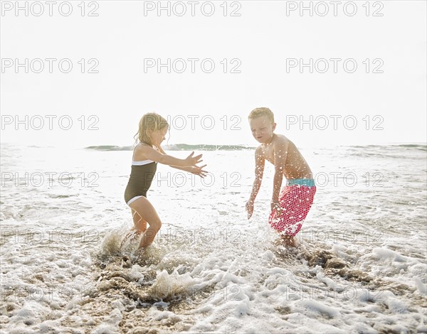 Mother walking with boy (6-7) and girl (4-5) on beach by water
